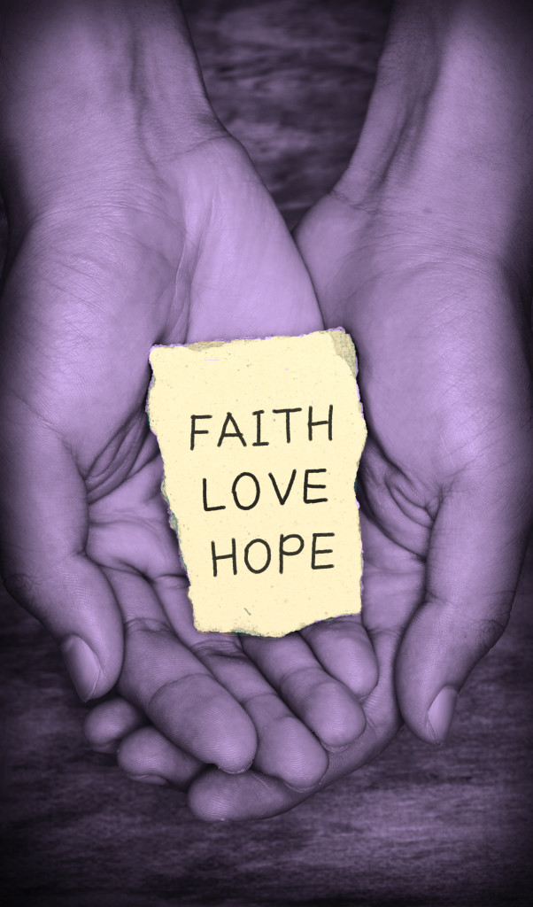 Faith Love Hope stone block in hands with dark background.